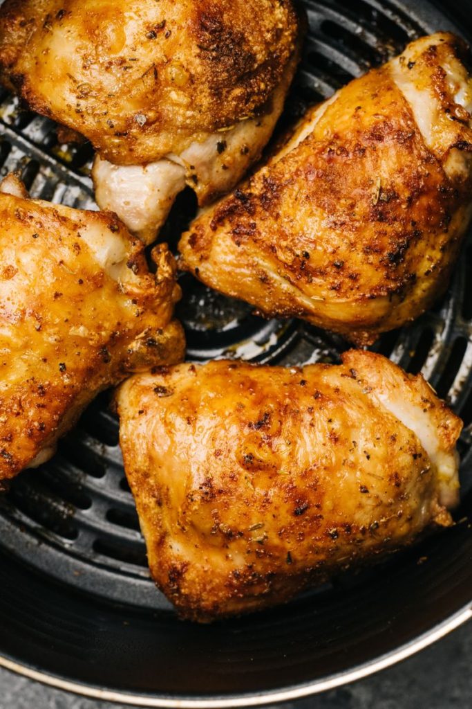 Cooked chicken in a black air fryer basket.