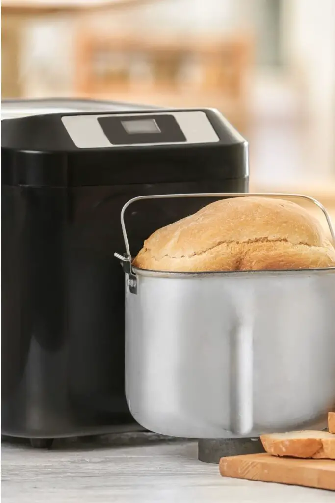 A bread machine with a bread machine basket containing a fresh loaf of bread
