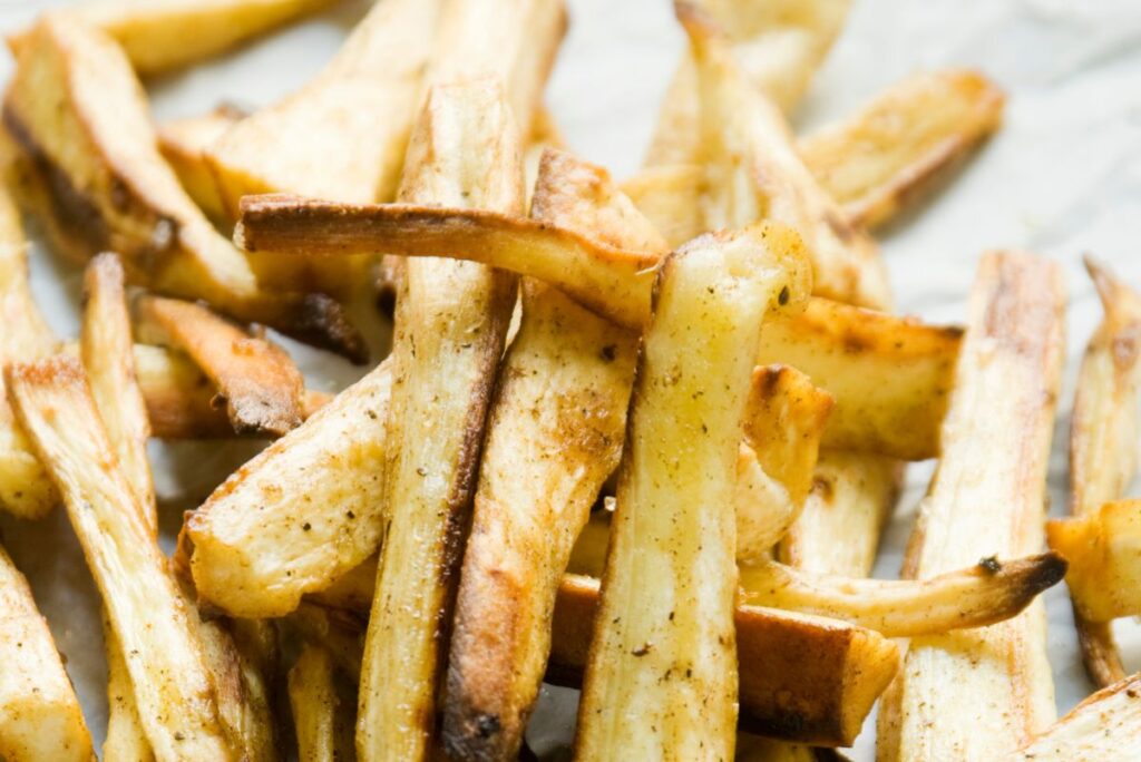 Parsnip fries in a pile on a white paper.