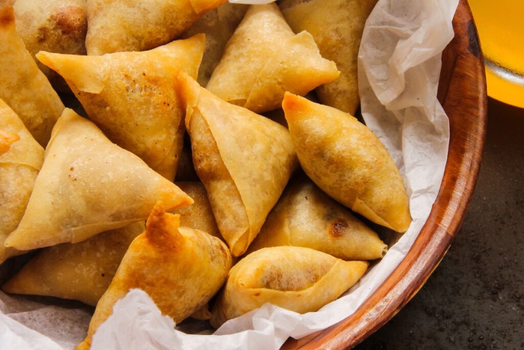 Samosas in a bowl lined with white paper.