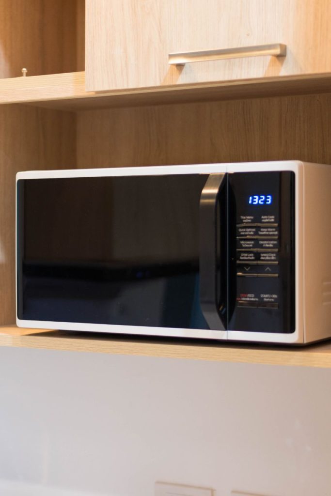 A white microwave sitting on a shelf.