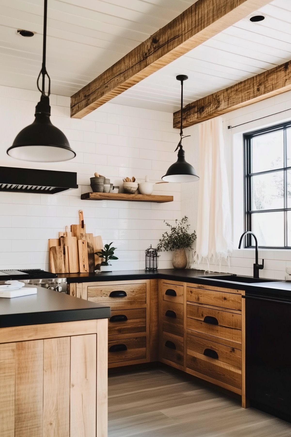 Rustic kitchen with natural wood cabinets, black countertops, industrial pendant lighting, white subway tile backsplash, exposed wooden beams, and a farmhouse-style black-framed window.