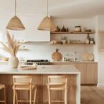 Minimalist kitchen design with natural tones, featuring light wood cabinets, rattan pendant lights, cane barstools, and open shelving styled with neutral decor and greenery.