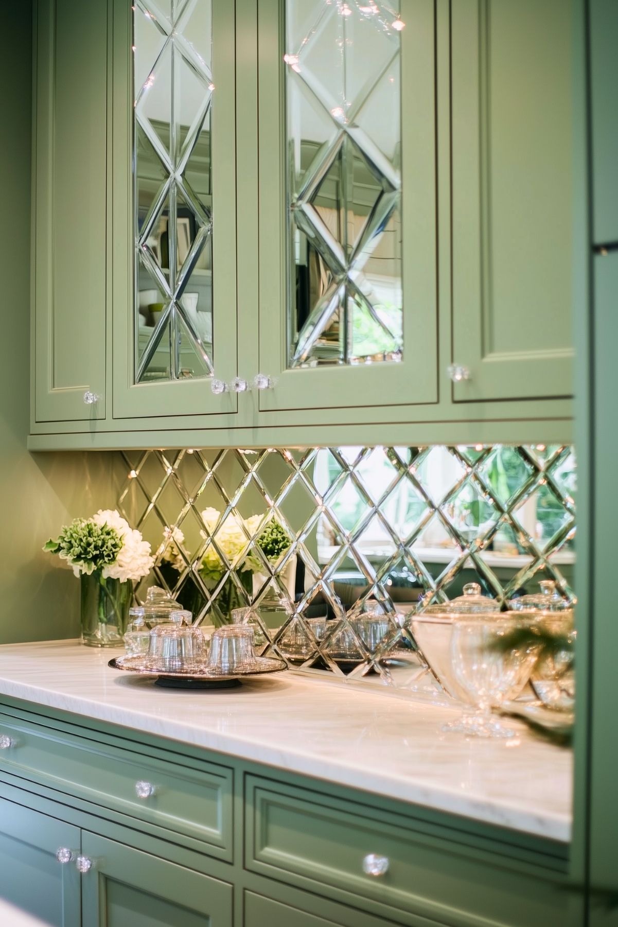 Sage green kitchen cabinetry with mirrored doors and diamond-patterned mirrored backsplash.