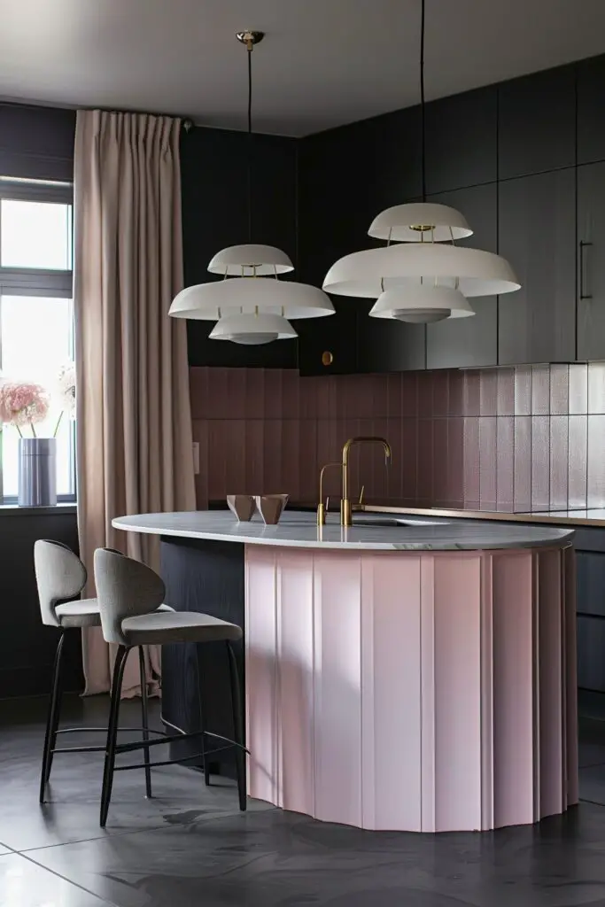 A contemporary kitchen featuring a pastel pink island with a marble countertop, paired with dark gray cabinetry. The island has a unique fluted design, and above it hang two modern, multi-tiered white pendant lights with brass accents. In the background, soft pink tiles create a subtle contrast with the dark cabinetry. Two sleek bar stools with gray upholstery sit at the island, adding to the kitchen's stylish and modern aesthetic. Light beige curtains frame the window, letting in natural light that highlights the room's sophisticated color palette.