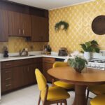 A yellow 1970s kitchen with a dining table with yellow chairs.