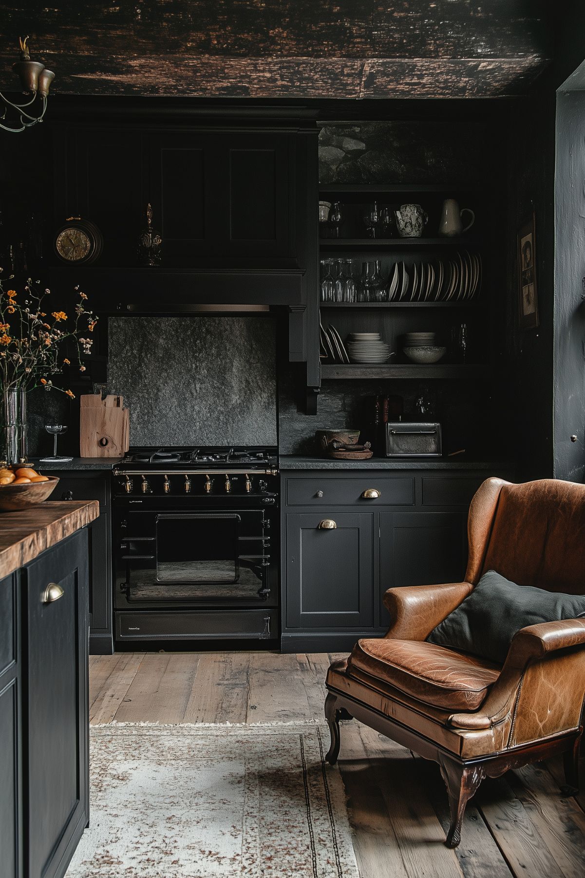 A kitchen with black cabinetry, a rustic wooden ceiling, and a vintage leather armchair. The open shelves display a collection of plates and glassware, creating a comfortable, lived-in space with a Dark Academia charm.