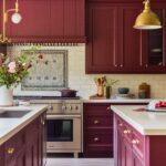 Burgundy kitchen featuring shaker-style cabinets, brass hardware, white quartz countertops, subway tile backsplash, a stainless steel oven, and gold pendant lighting.