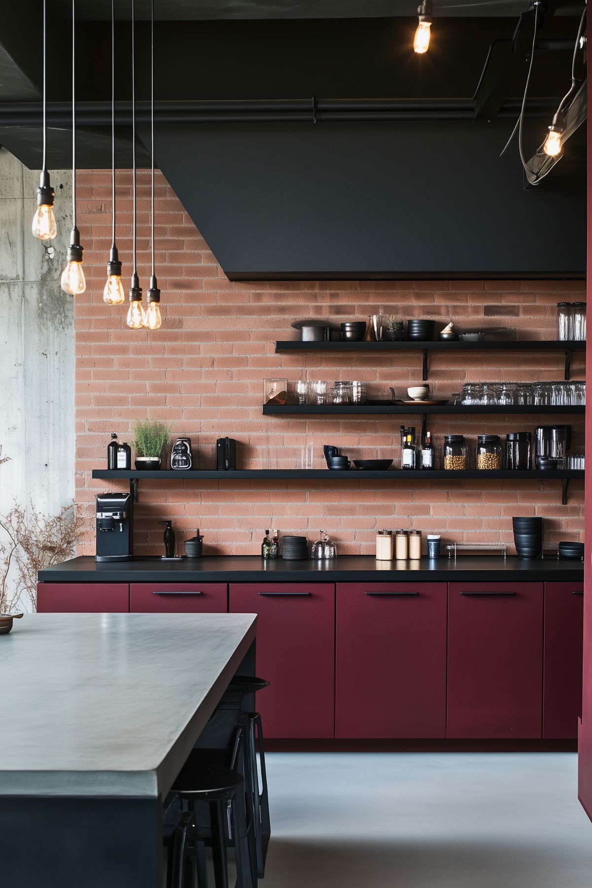 Industrial-style kitchen featuring burgundy cabinets with black countertops, open black shelving, a brick backsplash, concrete flooring, and exposed Edison bulb lighting.