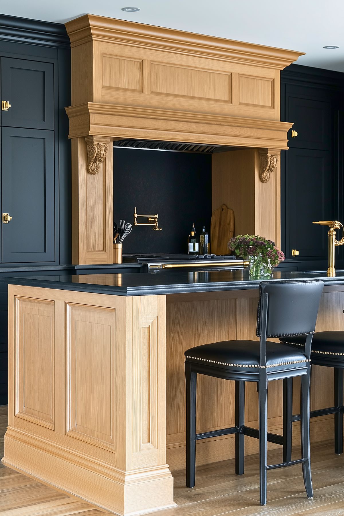 Luxurious kitchen with bold contrast between dark navy cabinetry and natural light oak details. Features an elegant wooden mantel hood, black leather bar stools, gold fixtures, and a black marble countertop, offering a sophisticated and contemporary aesthetic.