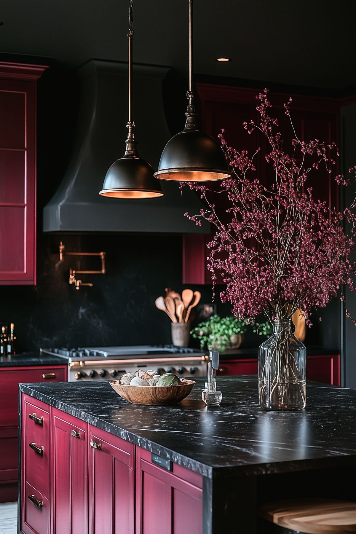 Moody kitchen with rich burgundy cabinets, a black marble island, dramatic lighting, and a tall floral arrangement adding elegance and depth.