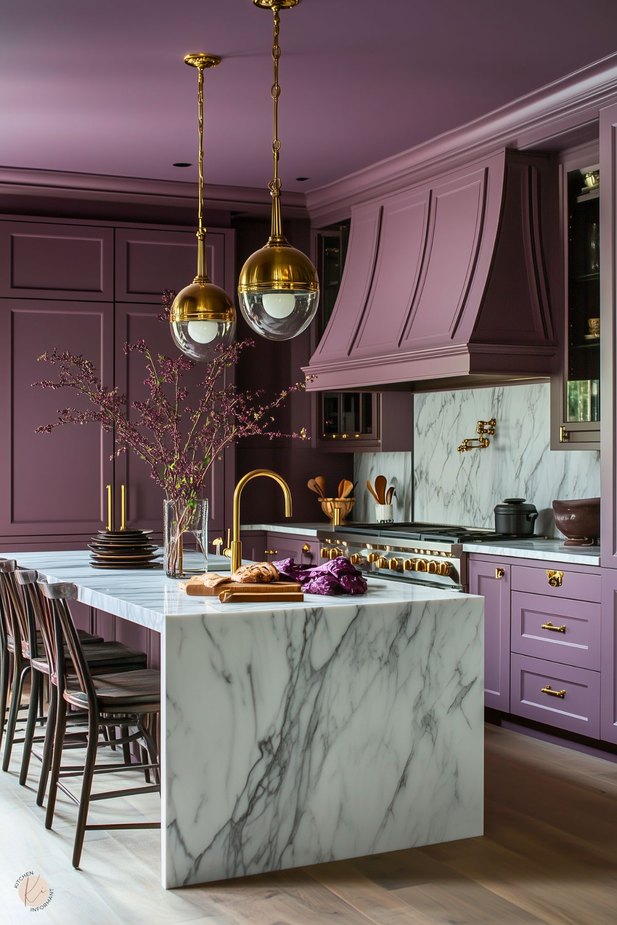 Luxurious kitchen with rich plum cabinetry, a dramatic marble island, and backsplash, accented by gold hardware and fixtures. The space features elegant globe pendant lights and a touch of greenery, creating a sophisticated and bold design.