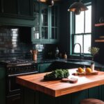 Moody kitchen with rich green cabinetry, glossy black subway tile backsplash, and a natural wood butcher block island. The space is accented with industrial-style pendant lighting, wooden stools, and a large window bringing in soft natural light for a dramatic yet inviting atmosphere.