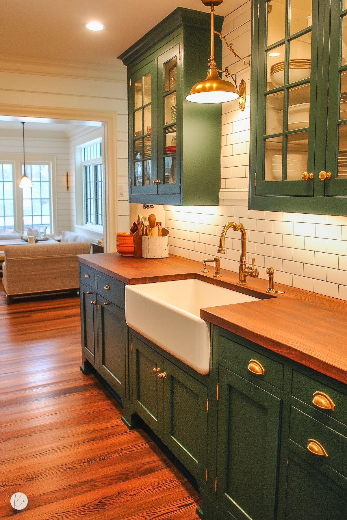 Classic kitchen with rich green cabinets, butcher block countertops, a farmhouse sink, brass fixtures, and white subway tile backsplash.