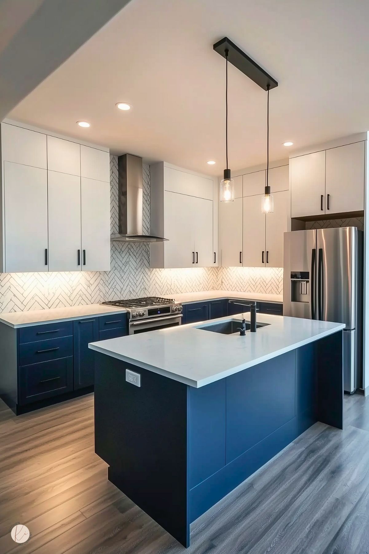 Modern kitchen with navy blue lower cabinets, white upper cabinets, a herringbone backsplash, and industrial pendant lighting over the island.