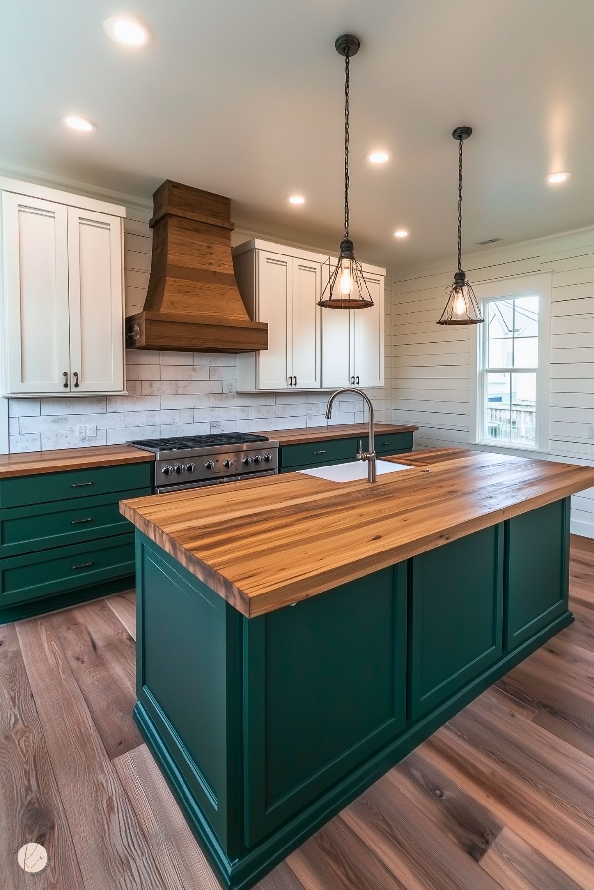 Rustic kitchen with forest green cabinets, butcher block countertops, a wooden range hood, and farmhouse-style pendant lighting.