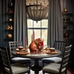 A dark academia dining room with deep navy walls, built-in shelving, and heavy drapes. A round black table is set with warm-toned dishware, red candles, and a bold floral centerpiece. Black grid-back chairs with plaid cushions surround the table. A large beaded chandelier adds drama, while gold accents on the shelves enhance the moody, sophisticated aesthetic.