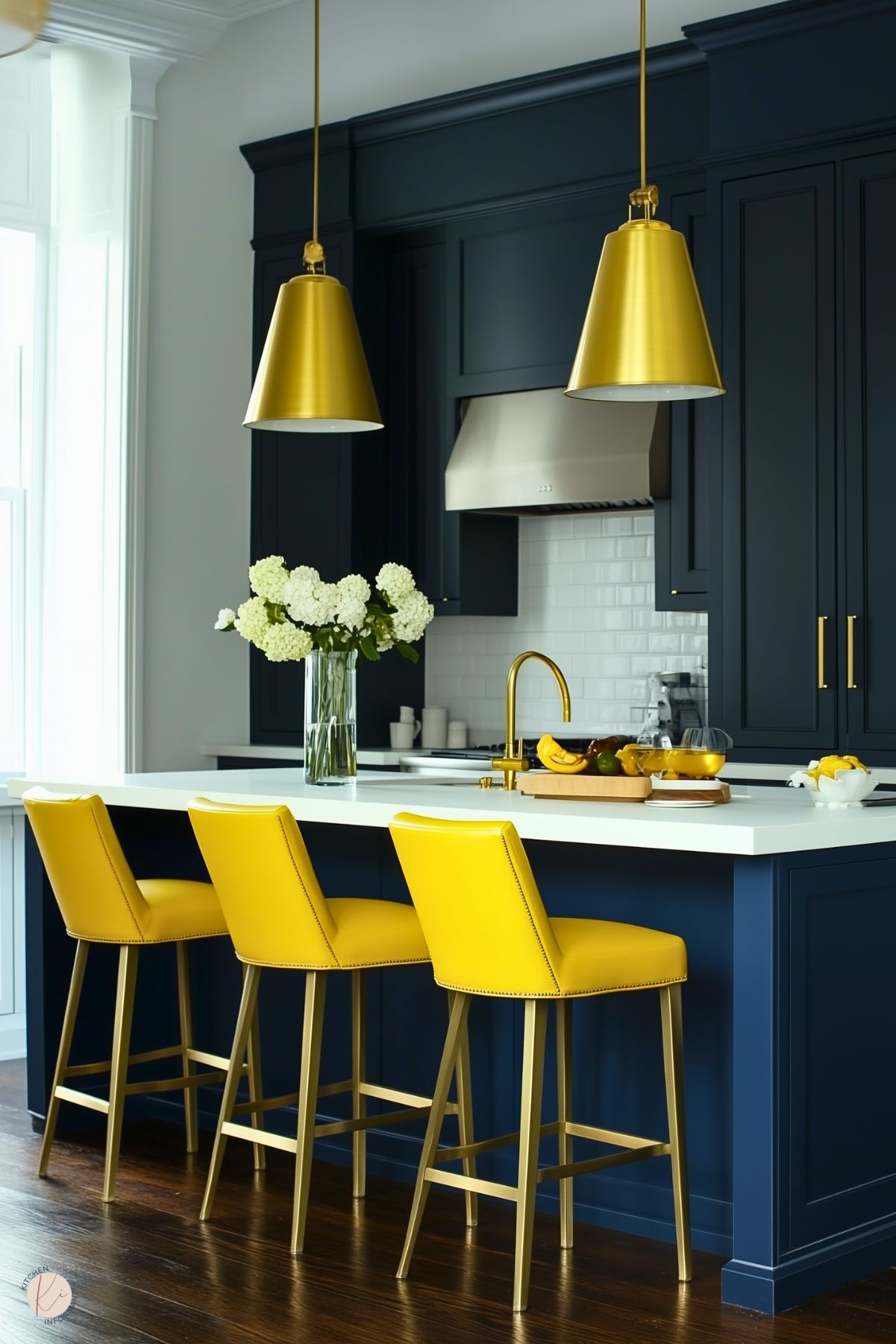 A striking preppy kitchen with navy cabinetry, bright yellow barstools, and matching gold pendant lights. The white countertop and subway tile backsplash provide a crisp contrast, while fresh floral accents add a touch of elegance.