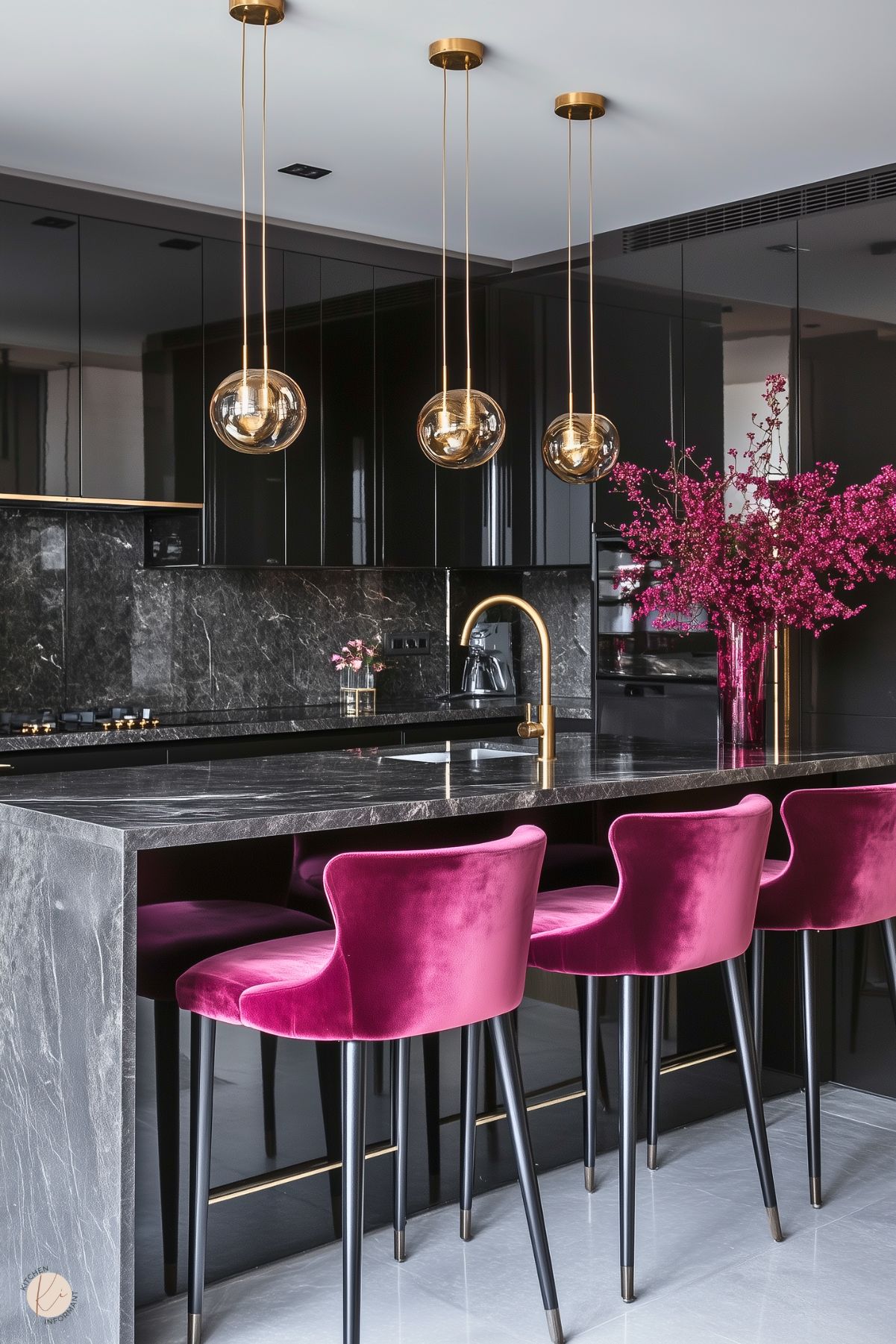 A luxurious kitchen featuring glossy black cabinets, a dark marble countertop, and a matching backsplash. The design is accented by gold fixtures, including a sleek faucet and pendant lights with globe-shaped shades. Vibrant magenta velvet bar stools provide a striking pop of color, complemented by a vase of matching magenta flowers on the counter. The space exudes modern elegance and bold sophistication.