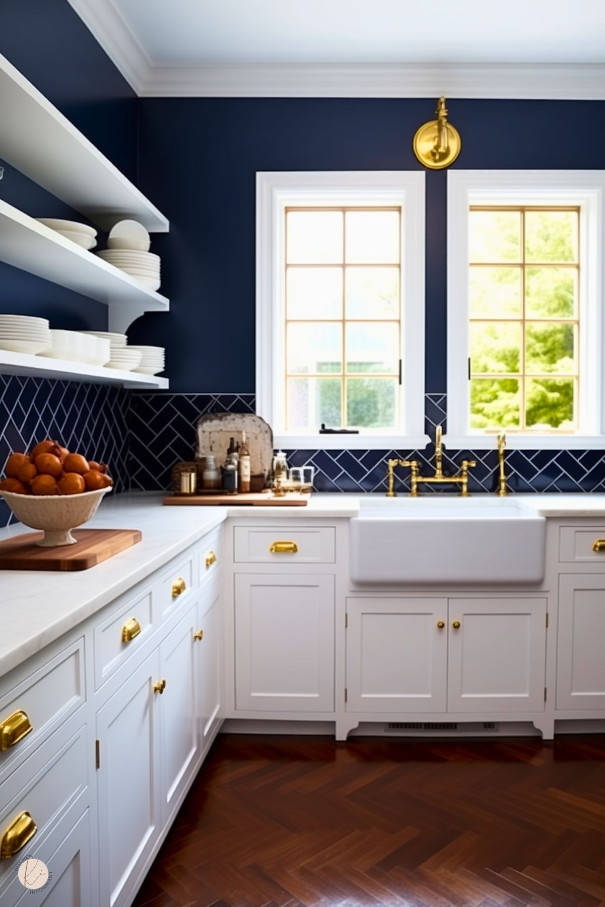 A sophisticated preppy kitchen with navy walls, white cabinetry, and a farmhouse sink. Gold hardware, a matching faucet, and a navy herringbone tile backsplash add refined details, complemented by rich wood herringbone flooring.