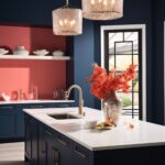 A contemporary kitchen with deep navy cabinetry, gold hardware, and a bold coral accent wall. The island features a crisp white countertop with a sleek gold faucet and is decorated with a metallic vase of vibrant orange foliage. Elegant pendant lights with textured shades hang above the island, adding a warm glow. A large window with black framing brings in natural light, balancing the rich color palette with brightness and sophistication. White dishes and minimal decor enhance the clean and modern aesthetic.