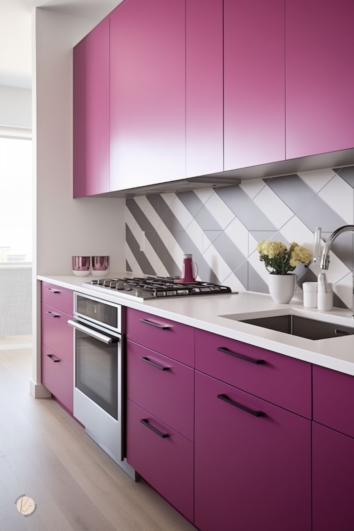 A kitchen with bold magenta cabinetry, sleek black hardware, and a white countertop. A geometric gray and white backsplash adds a modern touch. A built-in oven and gas cooktop are seamlessly integrated. Soft natural light brightens the space, while small decorative accents, including pink cups and a vase of flowers, enhance the stylish design.