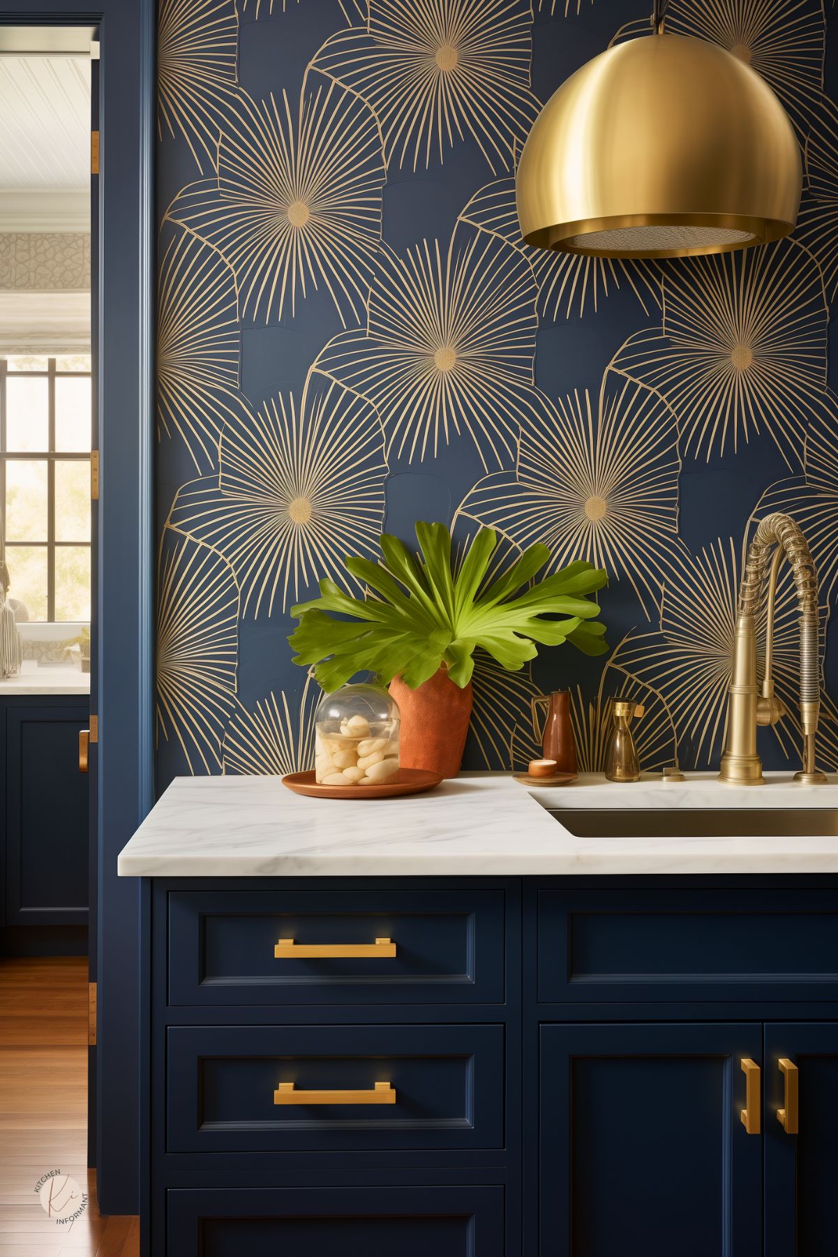 A kitchen with deep navy cabinetry and gold accents, featuring a bold wallpaper with oversized gold starburst patterns. A white marble countertop adds contrast, while brass hardware and a statement gold dome pendant light enhance the luxurious feel. A modern brass faucet and warm terracotta decor elements bring a balanced mix of elegance and warmth, creating a striking yet inviting space.