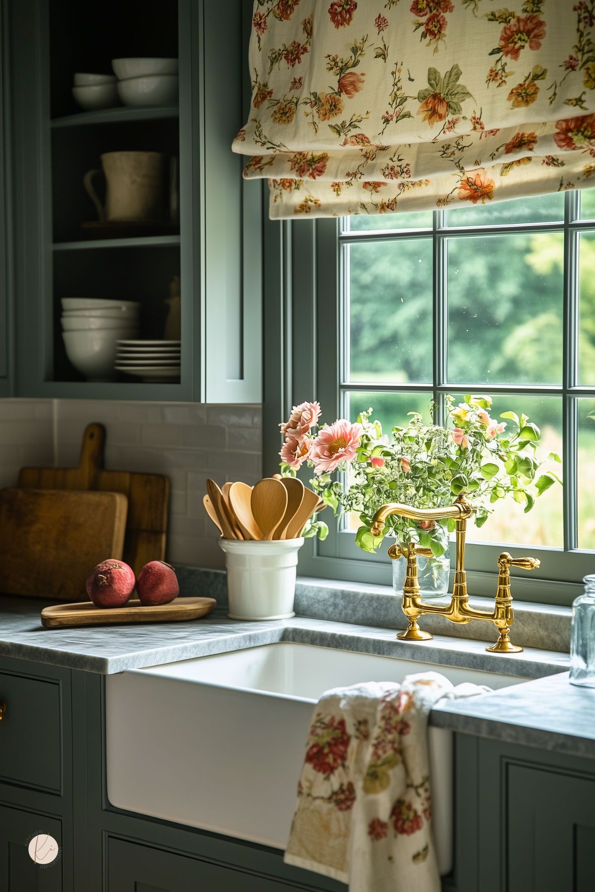 A charming English country kitchen with dark green cabinets, a farmhouse sink, and gold fixtures. Floral curtains and matching kitchen towel complement the fresh flowers on the marble countertop. Natural light fills the space, highlighting wooden utensils and rustic cutting boards.