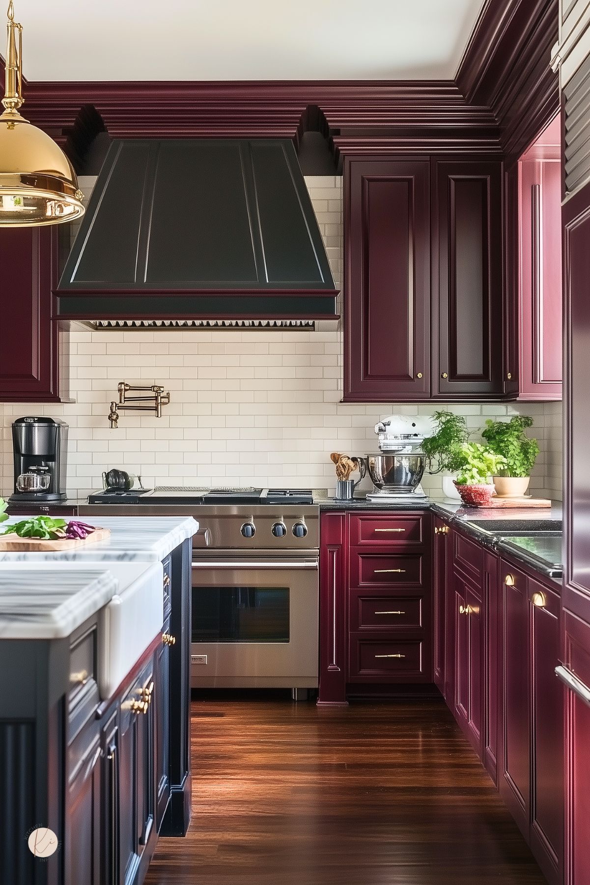 Traditional kitchen with burgundy cabinets, a black range hood, white subway tile backsplash, a farmhouse sink with marble countertops, stainless steel appliances, and rich dark wood flooring, creating a bold and timeless design.