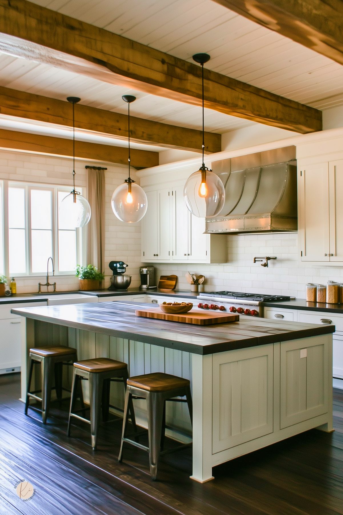 Bright and moody cottage kitchen with creamy white cabinetry, dark wood countertops, and a large island with vertical paneling. Exposed wood ceiling beams and industrial-style glass globe pendant lights add rustic charm. A stainless steel range hood and farmhouse sink complete the space, while wood stools and subtle decor keep the look cozy and welcoming.