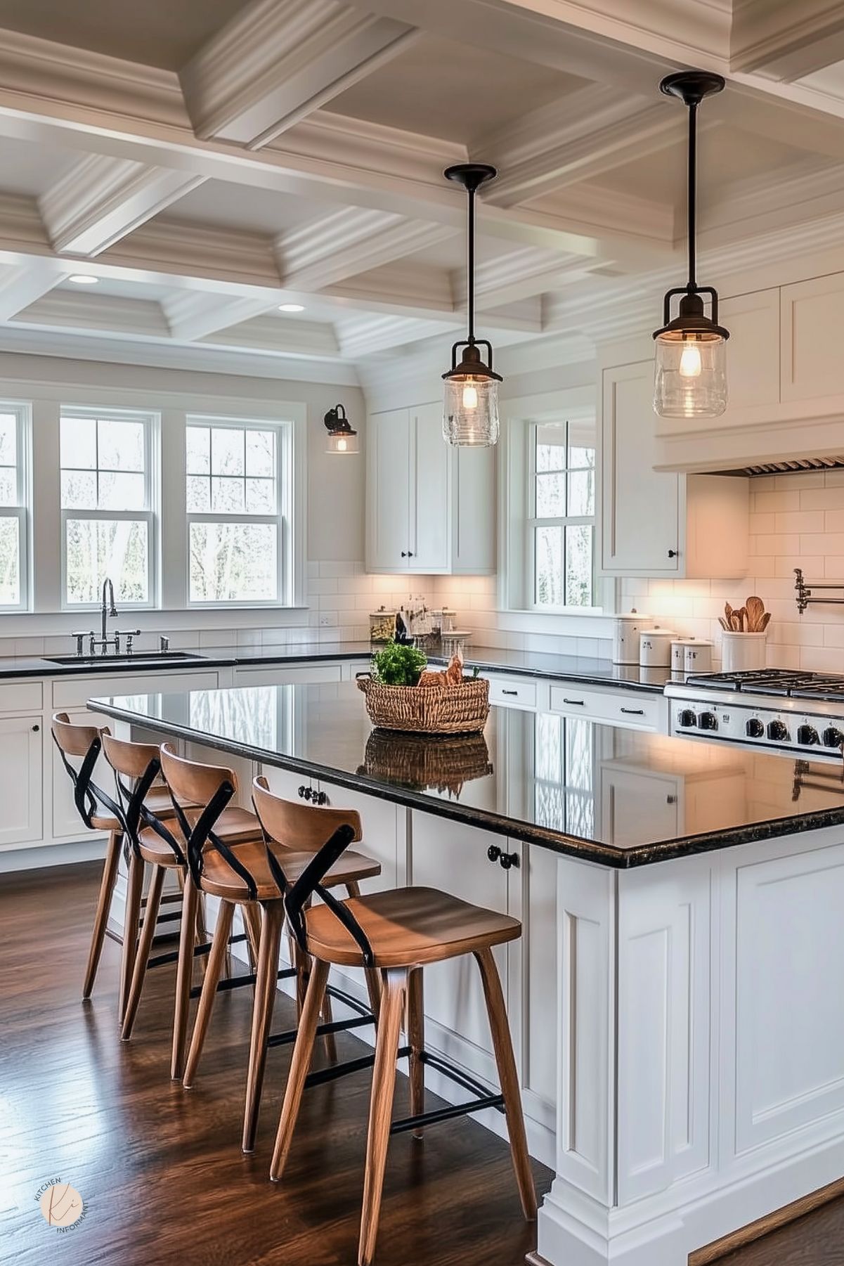 Bright kitchen with white cabinetry, a coffered ceiling, and dark stone countertops. A large island with seating for four features wood stools with black accents. Glass pendant lights hang above, adding a touch of industrial style. Multiple windows bring in natural light, while a basket of fresh greens decorates the island for a warm, timeless look.