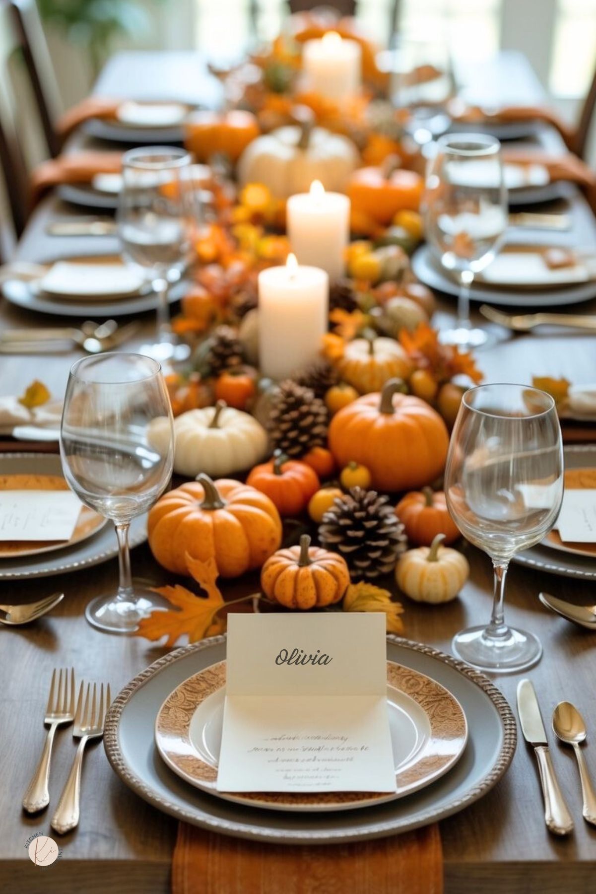 A Thanksgiving table set with plates, silverware, wine glasses, autumn decorations, candles, and place cards arranged for a festive meal.