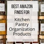 Neatly organized spice drawer with clear glass jars and bamboo lids, each labeled (Jamaican Jerk, Saffron, Sesame Seed, Chili Powder, Adobo, Paprika, Oregano, Rosemary, Garlic Powder). Text overlay: “BEST AMAZON FINDS FOR Kitchen Pantry Organization Products” and “kitcheninformant.com”.