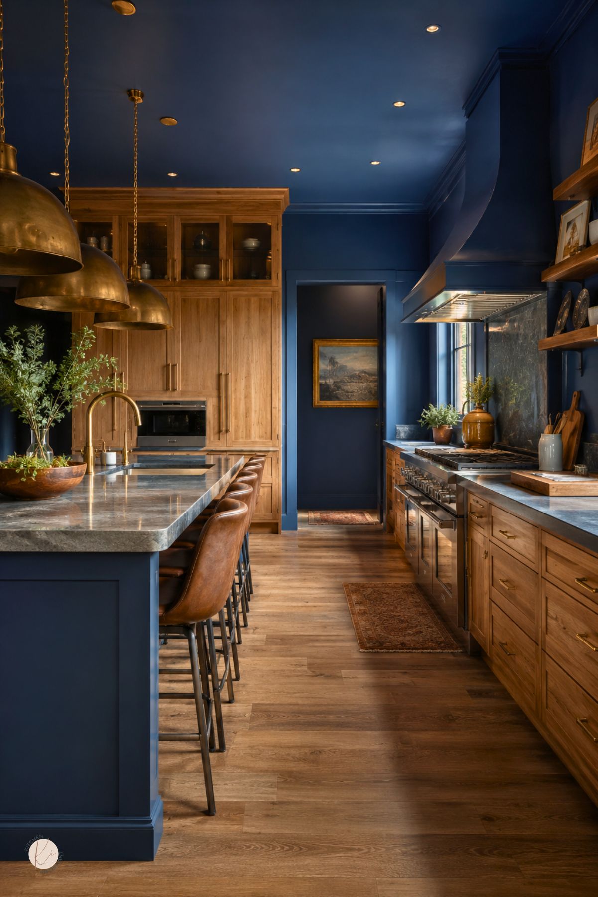 Moody blue kitchen with oak cabinets, a matching blue island, marble countertops, brass dome pendant lights, leather bar stools, wood flooring, open shelves, a blue range hood, and warm brass hardware.