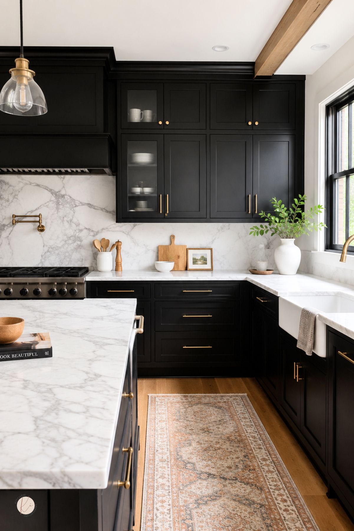 Black kitchen cabinets with brass hardware, white marble countertops, and a matching marble backsplash. A farmhouse sink, glass pendant light, wood ceiling beam, patterned runner rug, and warm wood floors create a polished modern farmhouse kitchen design.