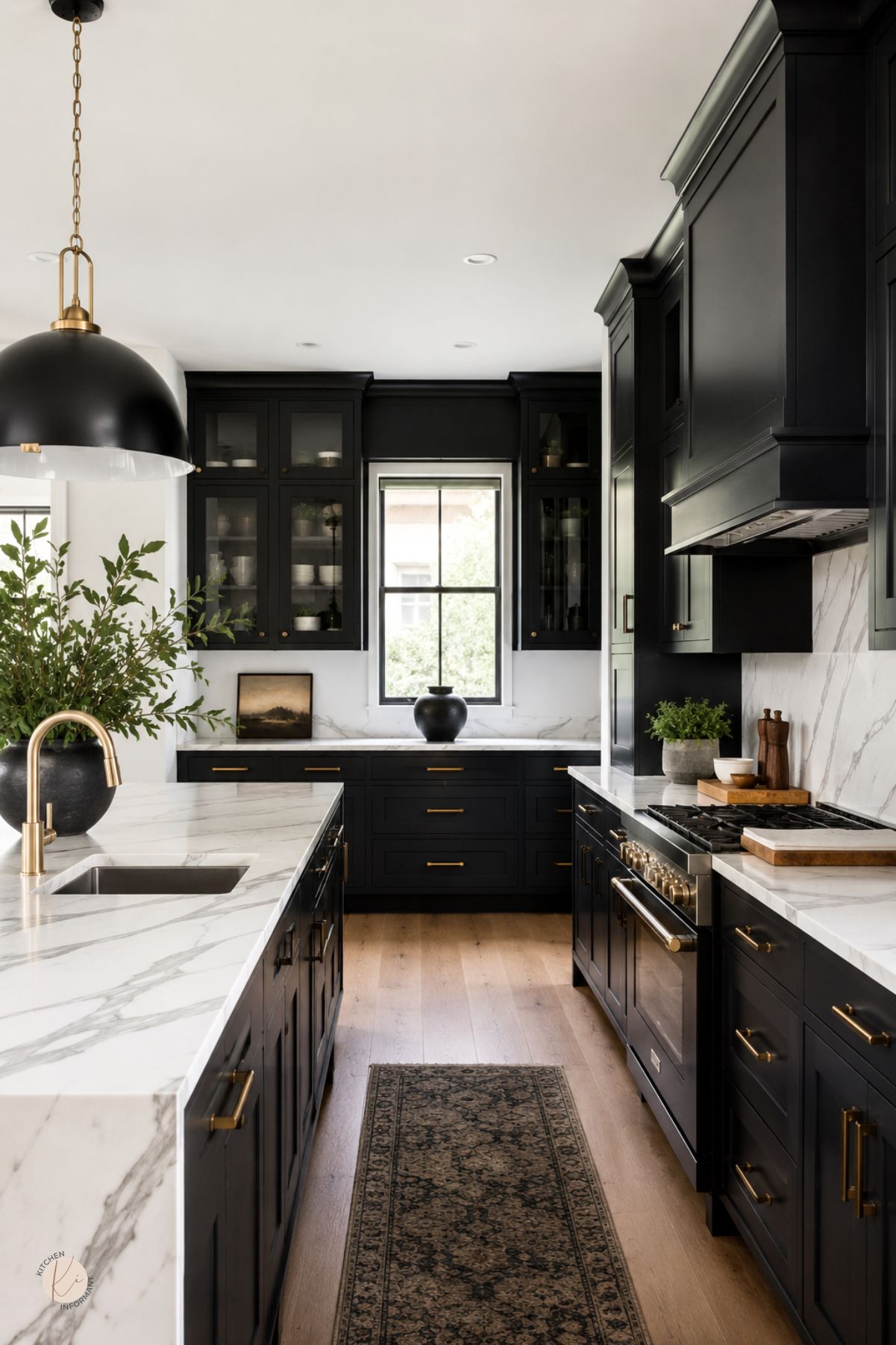 Black kitchen cabinets with brass hardware, white marble countertops, and a matching marble backsplash. A large marble island, black pendant light, brass faucet, glass-front cabinets, wood floors, and patterned runner rug create a dramatic modern kitchen design.